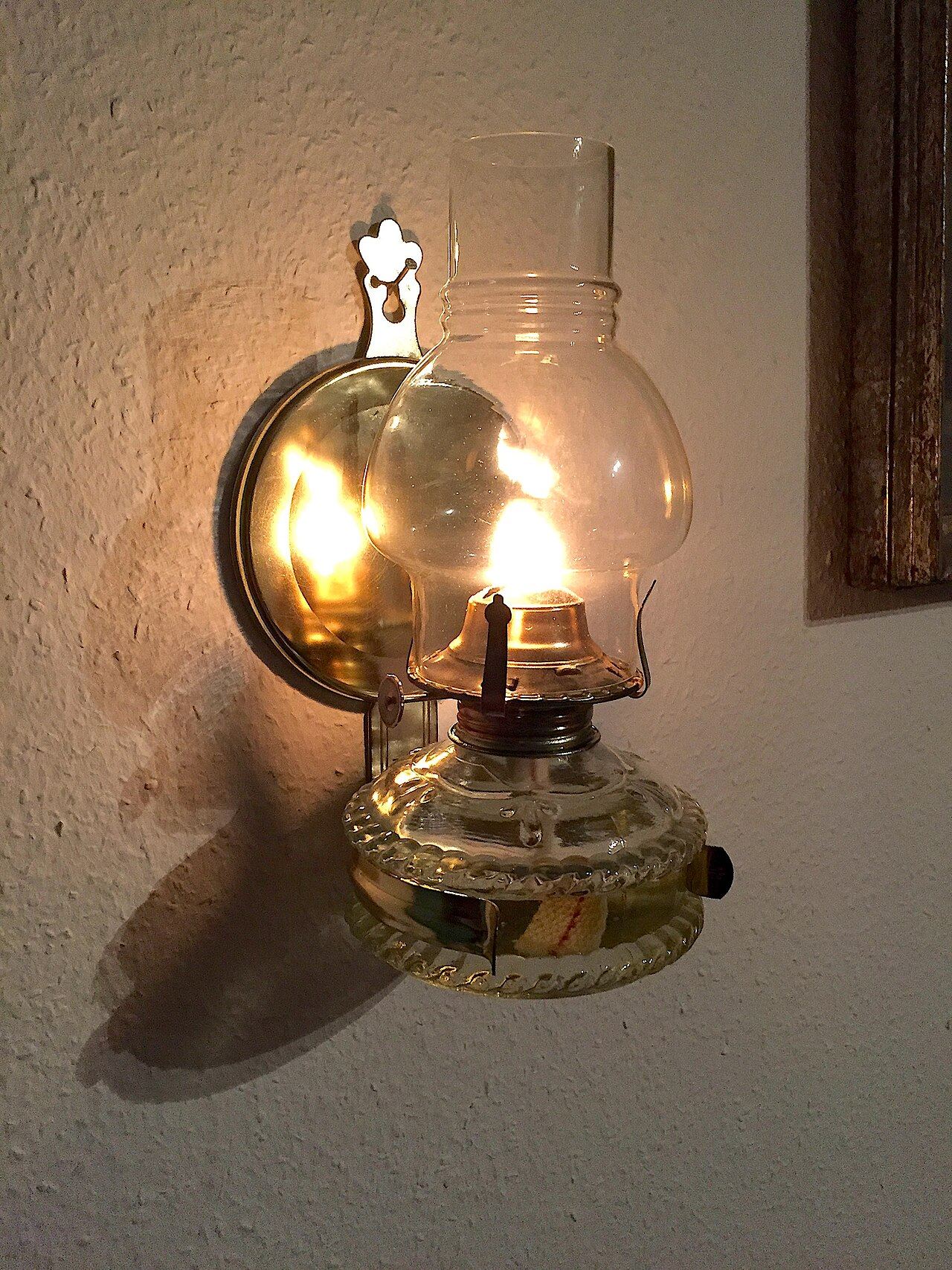 An oil lamp glowing against a whitewashed wall